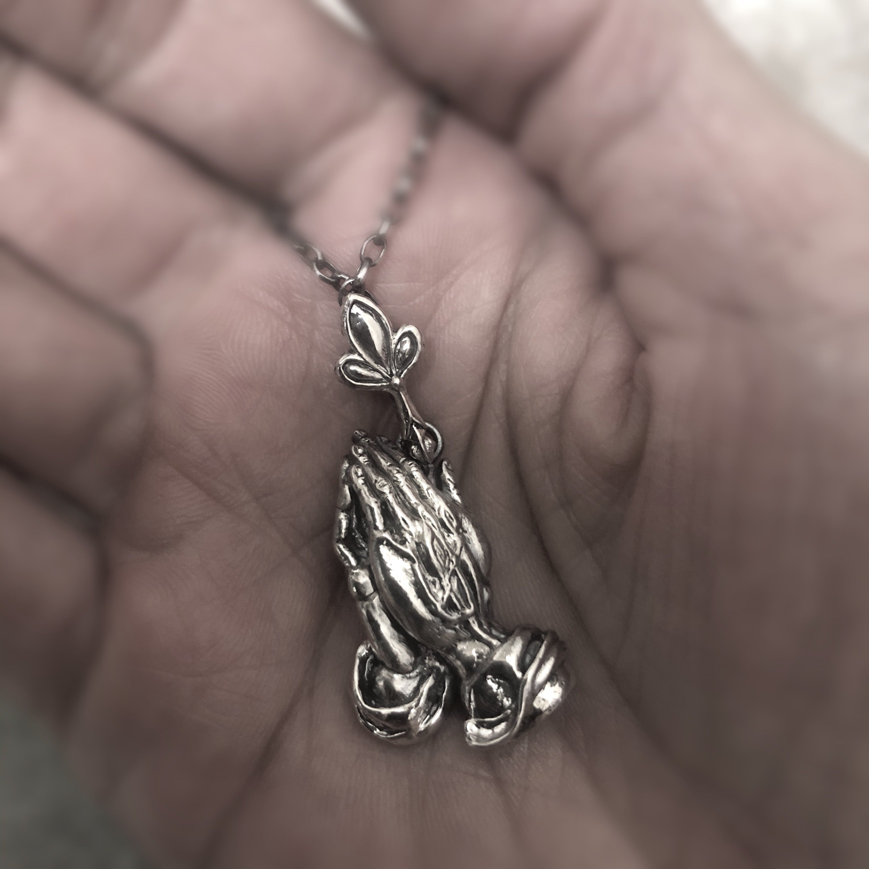 Collar de plata detallado / manos de oración