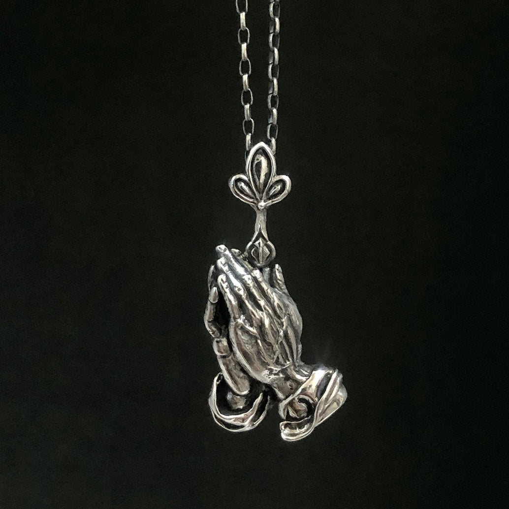 Collar de plata detallado / manos de oración